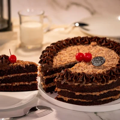 Suaves capas de bizcocho de chocolate, relleno y cubierto con una mezcla de ralladura de coco y nueces. Una explosión de sabores en cada rebanada. Encuentra el más delicioso Pastel Alemán en nuestra pastelería en Chihuahua. Endulza tus eventos con calidad.