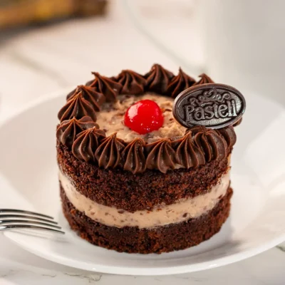 Suaves capas de bizcocho de chocolate, relleno y cubierto con una mezcla de ralladura de coco y nueces. Una explosión de sabores en cada rebanada. Encuentra el más delicioso Pastel Alemán en nuestra pastelería en Chihuahua. Endulza tus eventos con calidad.