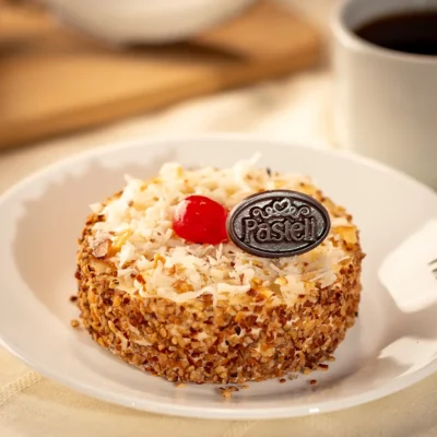 Un esponjoso Pan Genoise humedecido en jarabe de vainilla, cubierto con deliciosa lluvia de nuez y una suave capa de Coco Ángel. Una delicia celestial en cada bocado. Sorprende a tus invitados con repostería fina, servicio a domicilio disponible en Chihuahua.