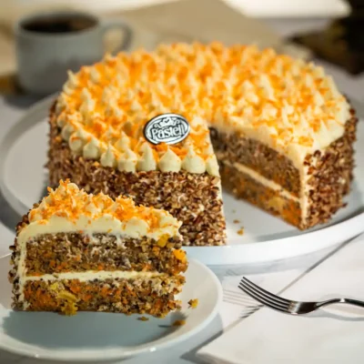 Esponjoso bizcocho de Zanahoria decorado con una Crema de queso estilo Pasteli y trozos de zanahoria caramelizada, con nueces alrededor. El tradicional pastel de zanahoria con el toque Pasteli. Repostería artesanal de alta calidad para tus fiestas en Chihuahua.